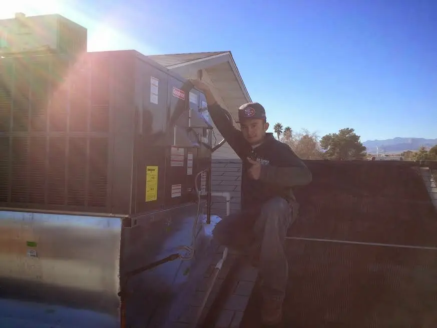 HVAC technician performing Air Duct Cleaning on a rooftop unit in Bartonville